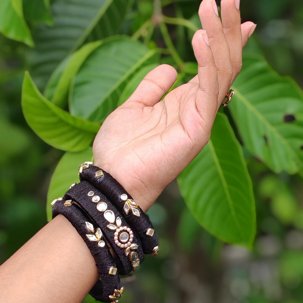 Black silk thread bangles with gold stones worn on the wrist