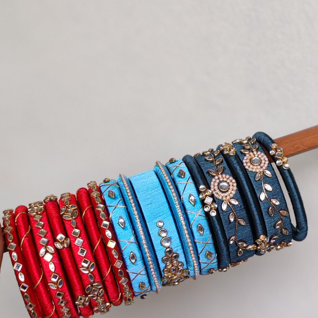 Red and blue silk thread bangle sets on a wooden stand